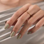 Model wearing a dainty gold chevron ring with baguette diamonds on her finger. Elegant V-shaped curved wedding band.