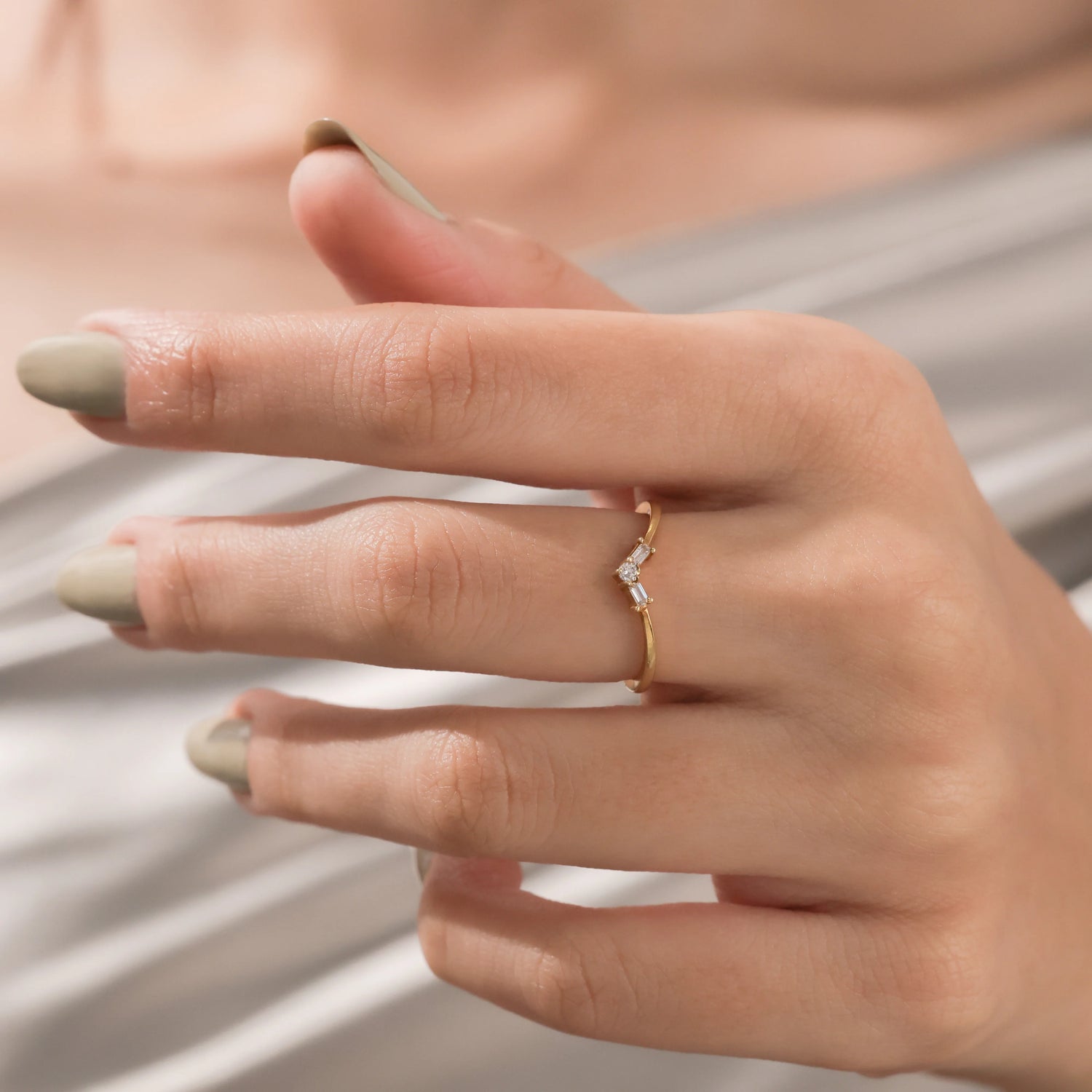 Gold V-ring featuring a round center stone and baguette diamonds worn on a finger. Delicate curved nesting band for stacking. 