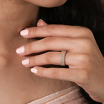 Close-up of a woman's hand with yellow gold round and princess diamond engagement ring, resting gently on her neck.