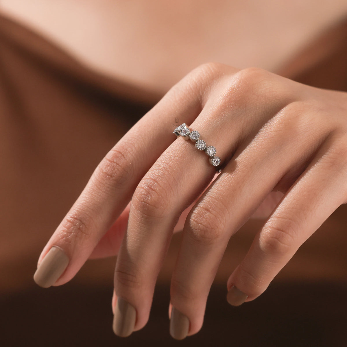 Hand displaying an elegant white gold diamond zig-zag band, showcasing alternating round brilliant stones in bezel set wedding band.