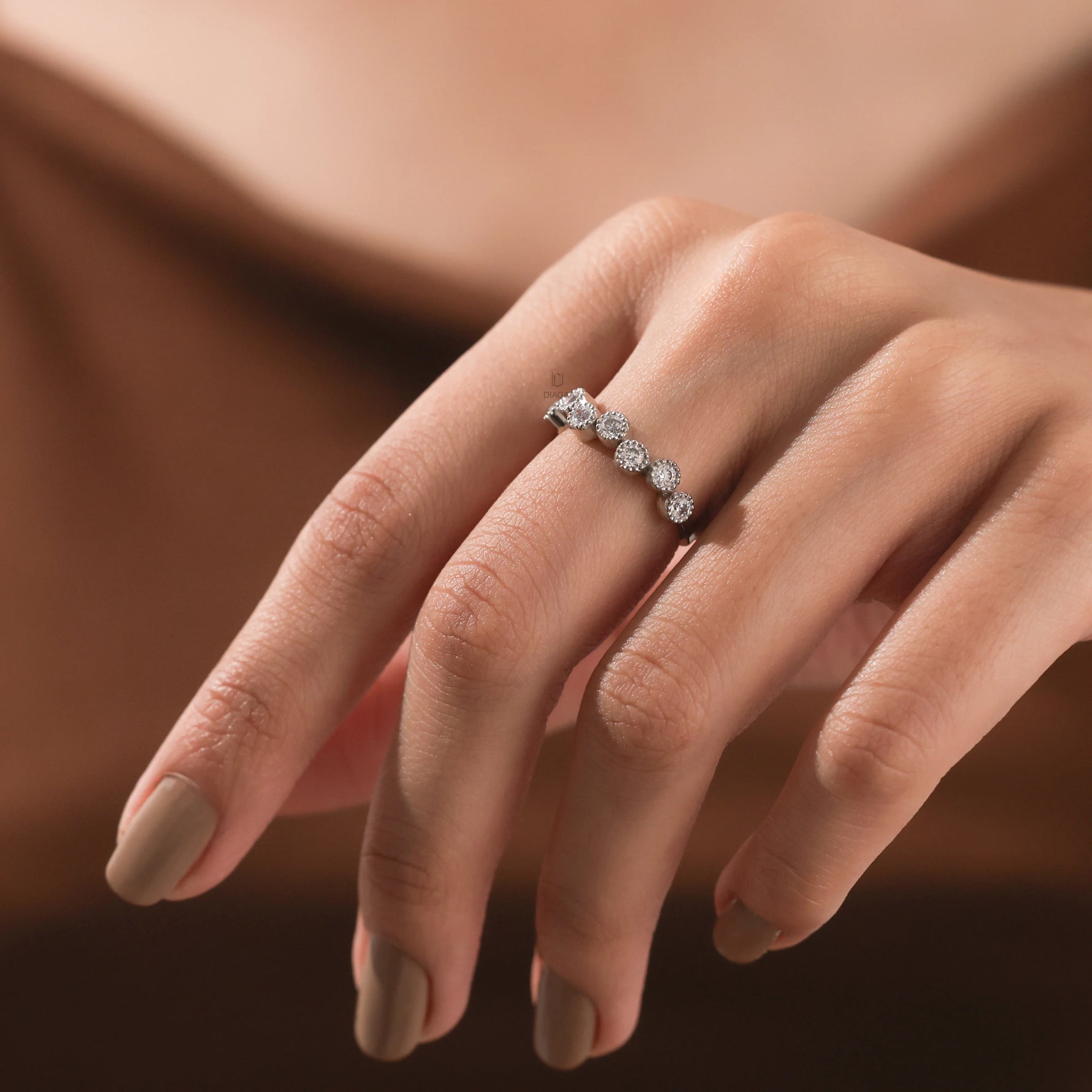 Hand displaying an elegant white gold diamond zig-zag band, showcasing alternating round brilliant stones in bezel set wedding band.