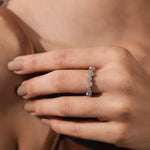 Woman wearing an elegant  steling silver stackable wedding ring with an alternating high-low round diamond bezel setting band.
