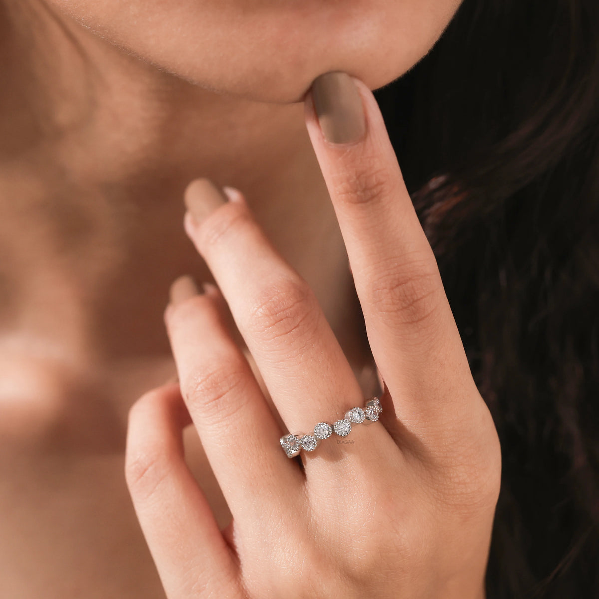 Woman wearing an elegant white gold stackable wedding ring with an alternating high-low round diamond bezel setting band.