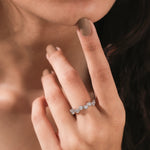 Woman wearing an elegant white gold stackable wedding ring with an alternating high-low round diamond bezel setting band.