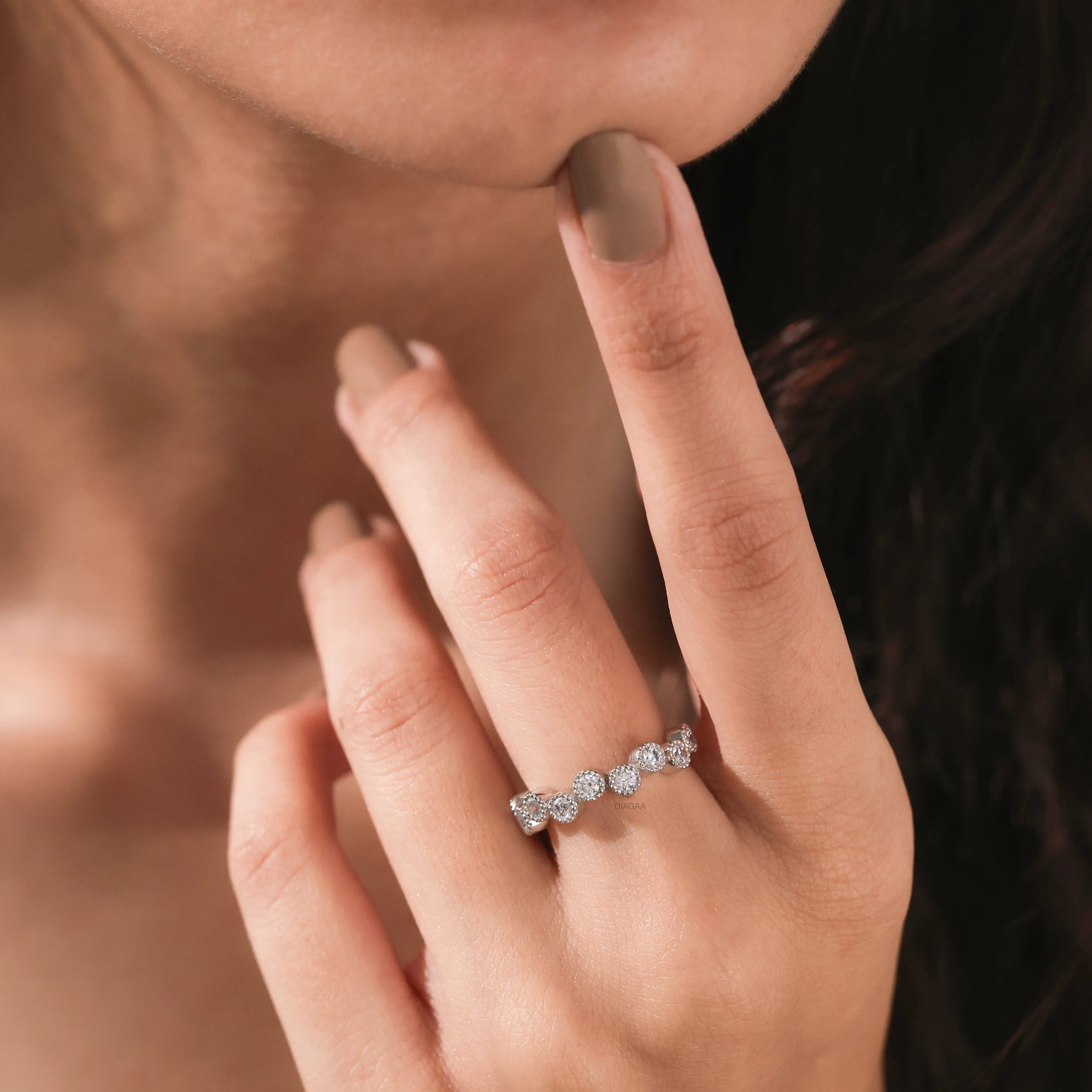 Woman wearing an elegant white gold stackable wedding ring with an alternating high-low round diamond bezel setting band.