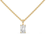 Front view of a solitaire emerald diamond necklace in yellow gold, highlighting a delicate prong-set emerald-cut stone suspended from a cable chain with a white background. 