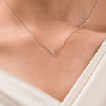 Woman wearing a delicate three-stone round diamond necklace featuring a prong-set cluster in 14K white gold.