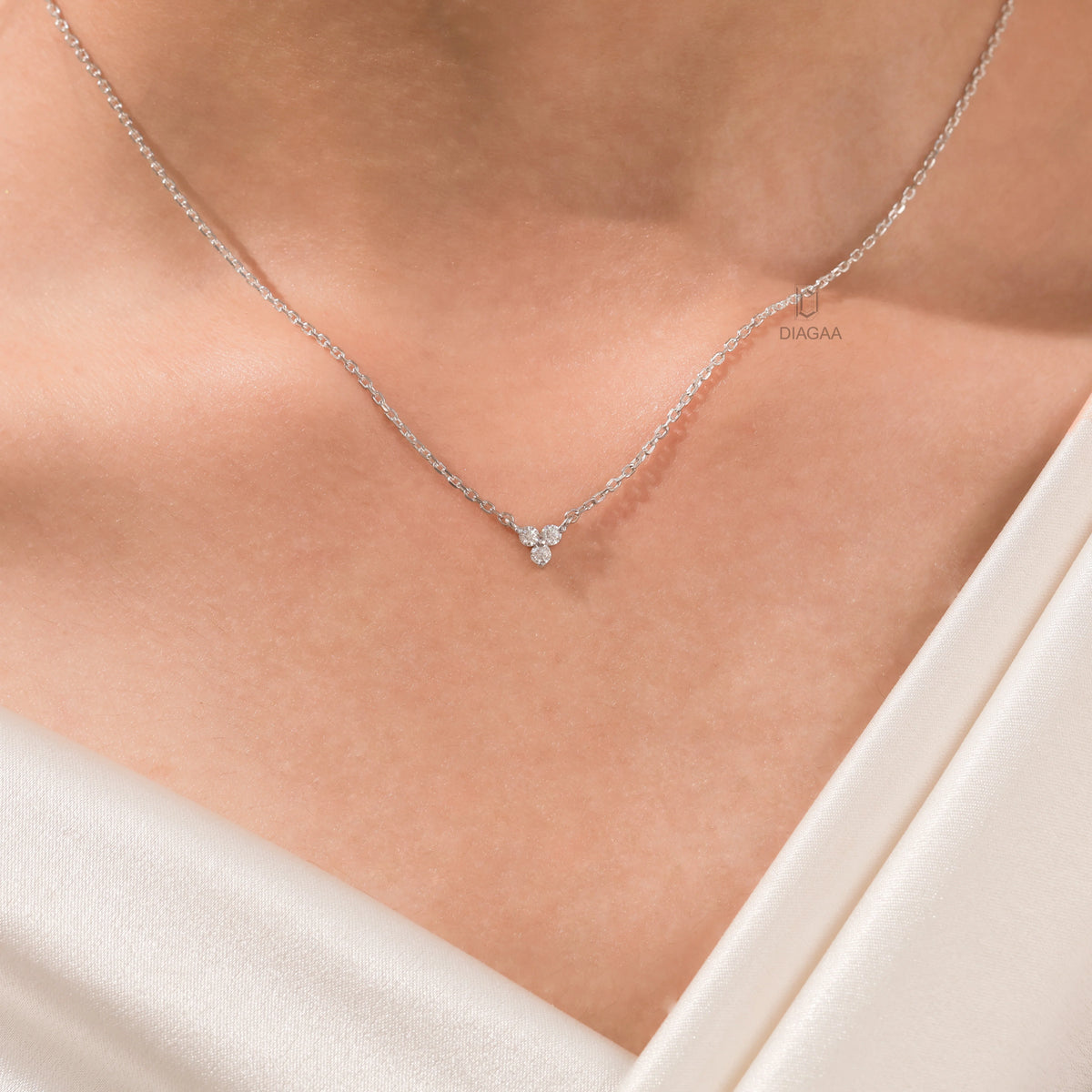 Woman wearing a delicate three-stone round diamond necklace featuring a prong-set cluster in 14K white gold.