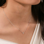 Woman wearing a delicate three-stone round diamond necklace featuring a prong-set cluster in white gold.
