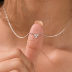 Woman wearing a delicate three-stone round diamond necklace featuring a prong-set cluster in white gold.