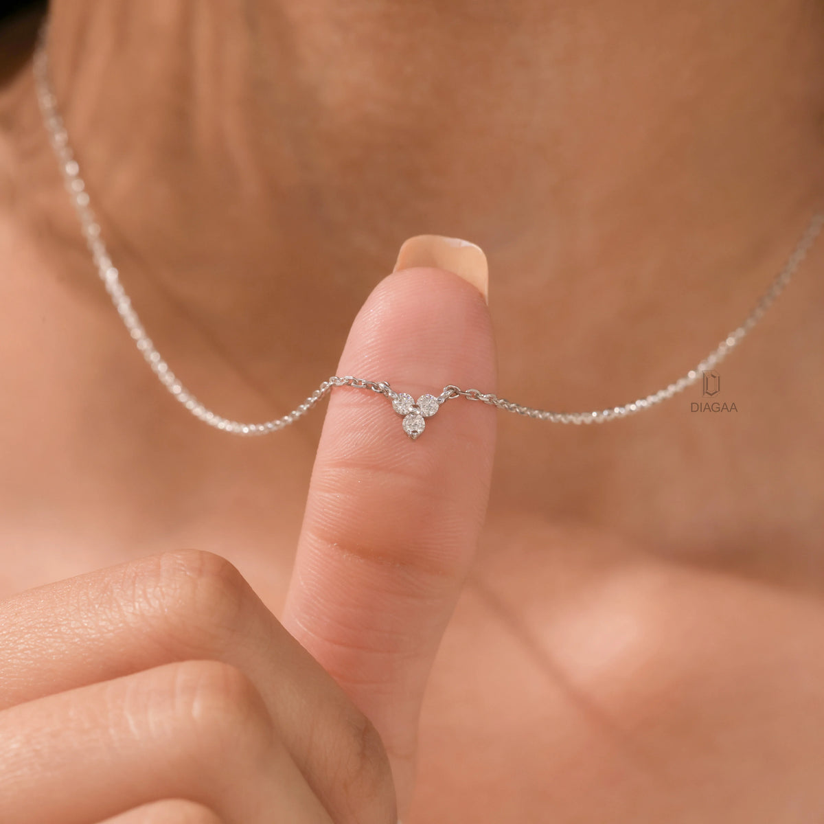 Woman wearing a delicate three-stone round diamond necklace featuring a prong-set cluster in white gold.