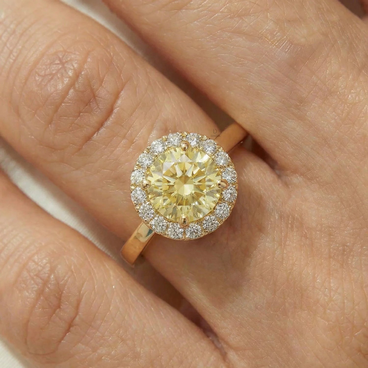 Elegant round yellow diamond halo engagement ring in yellow gold,modeled gracefully on a woman's hand.