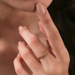 Close-up of a delicate gold cluster ring with a staggered double row of small diamonds worn on a woman's hand.
