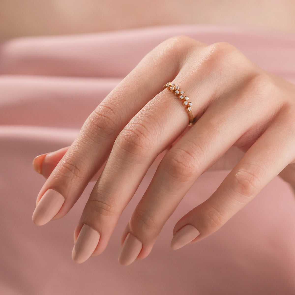 Elegant women's fine jewelry: a thin yellow gold ring with a sparkling diamond cluster, worn on a ring finger with zig-zag round diamond wedding band 