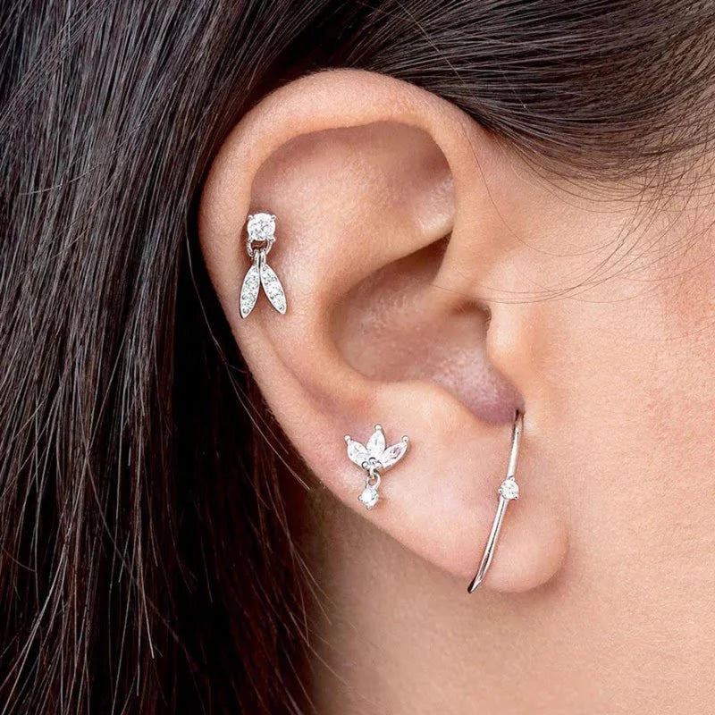 Model wearing a silver round diamond dangle earring in a helix cartilage piercing, paired with stacked minimalist earrings for a curated ear look.