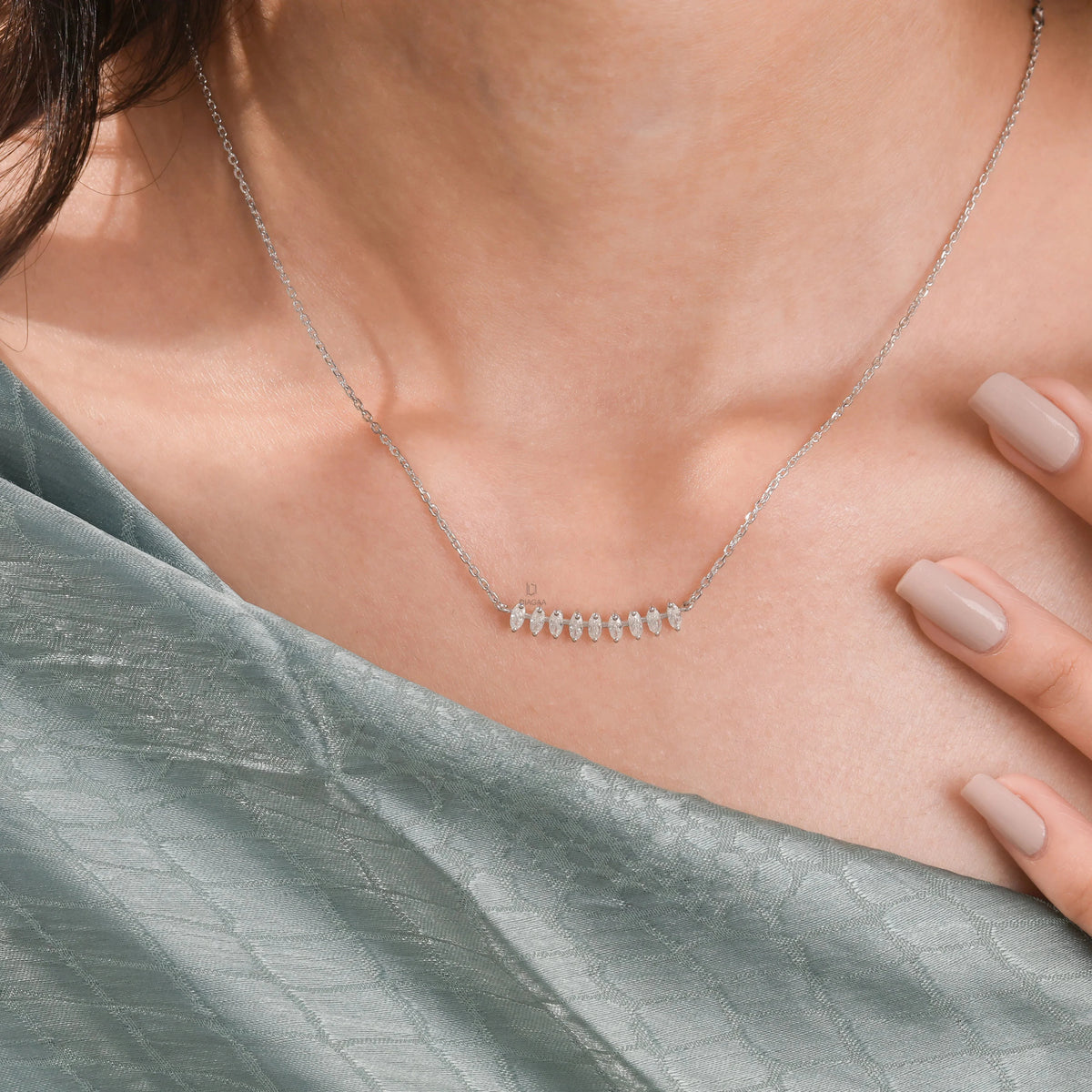 Woman wearing a fine yellow gold marquise diamond necklace featuring prong-set stones along a delicate curved bar.