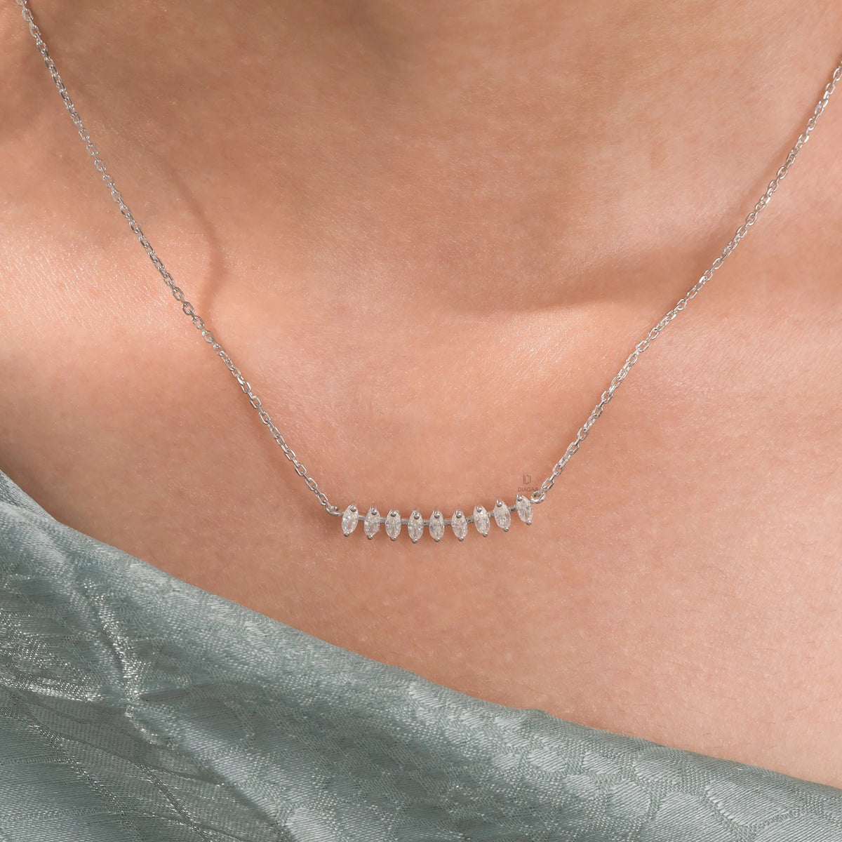 Woman wearing a fine 14K white gold marquise diamond necklace featuring prong-set stones along a delicate curved bar.