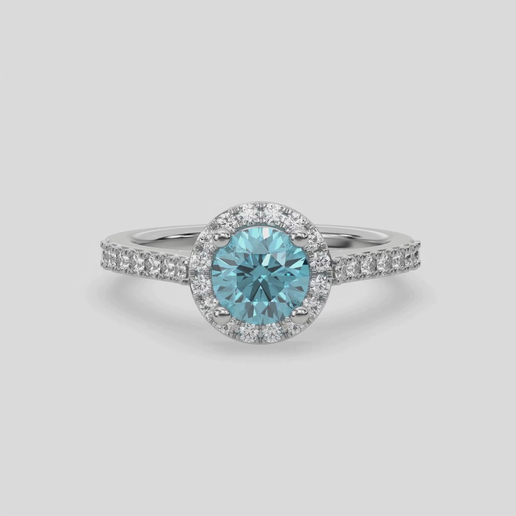 This video features a white gold Round Diamond Halo Engagement Ring is made with a fancy Blue round solitaire diamond set in a four-prong setting