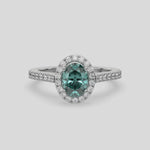 This video features a white gold Oval Diamond Halo Engagement Ring is made with a fancy green oval solitaire diamond set in a four-prong setting, surrounded by a halo of round diamonds all set on a pave band