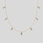 Emerald Dangling Diamond Necklace made with seven emerald cut diamonds each set in a prong setting, distributed evenly along the chain