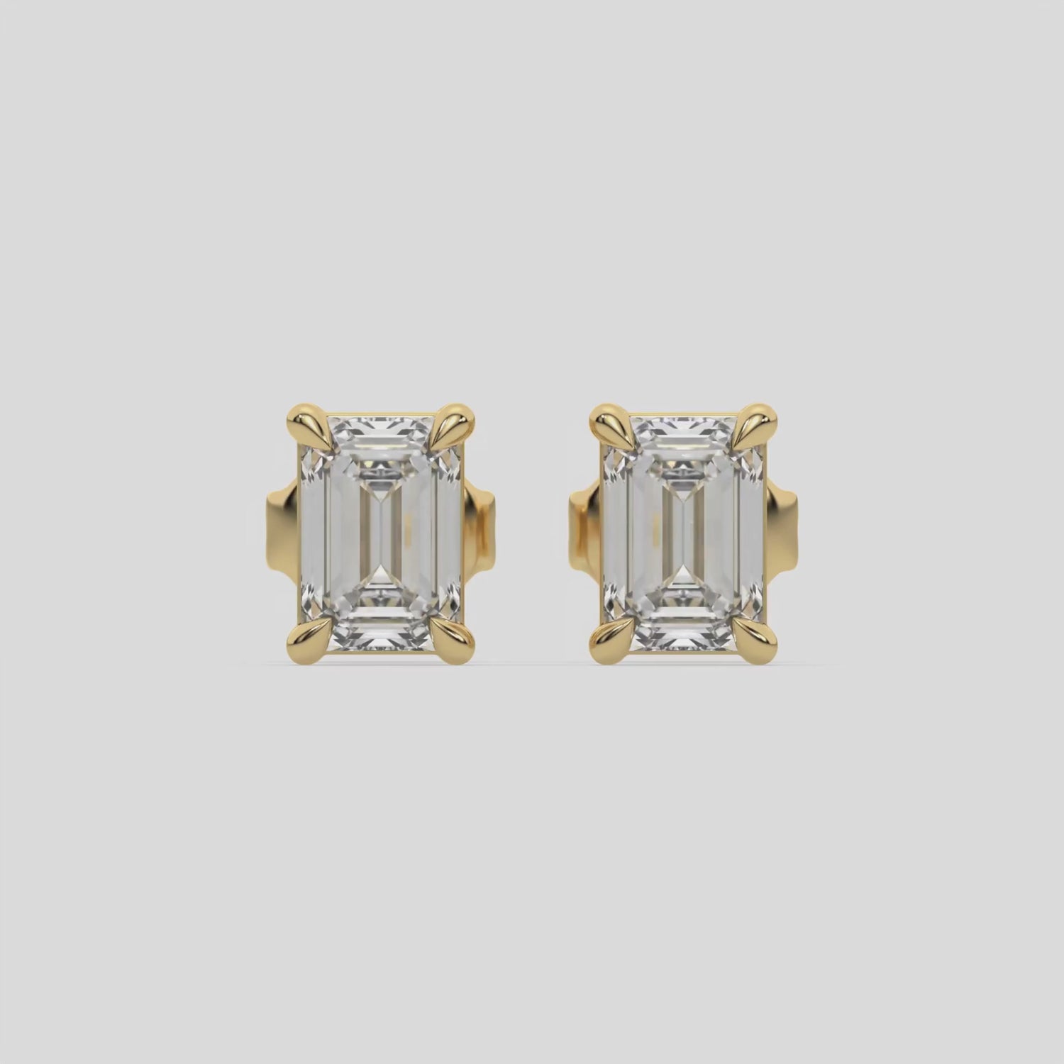 This video features a yellow gold Classic Emerald Diamond Earrings made with an emerald-cut diamonds set in a four prong setting