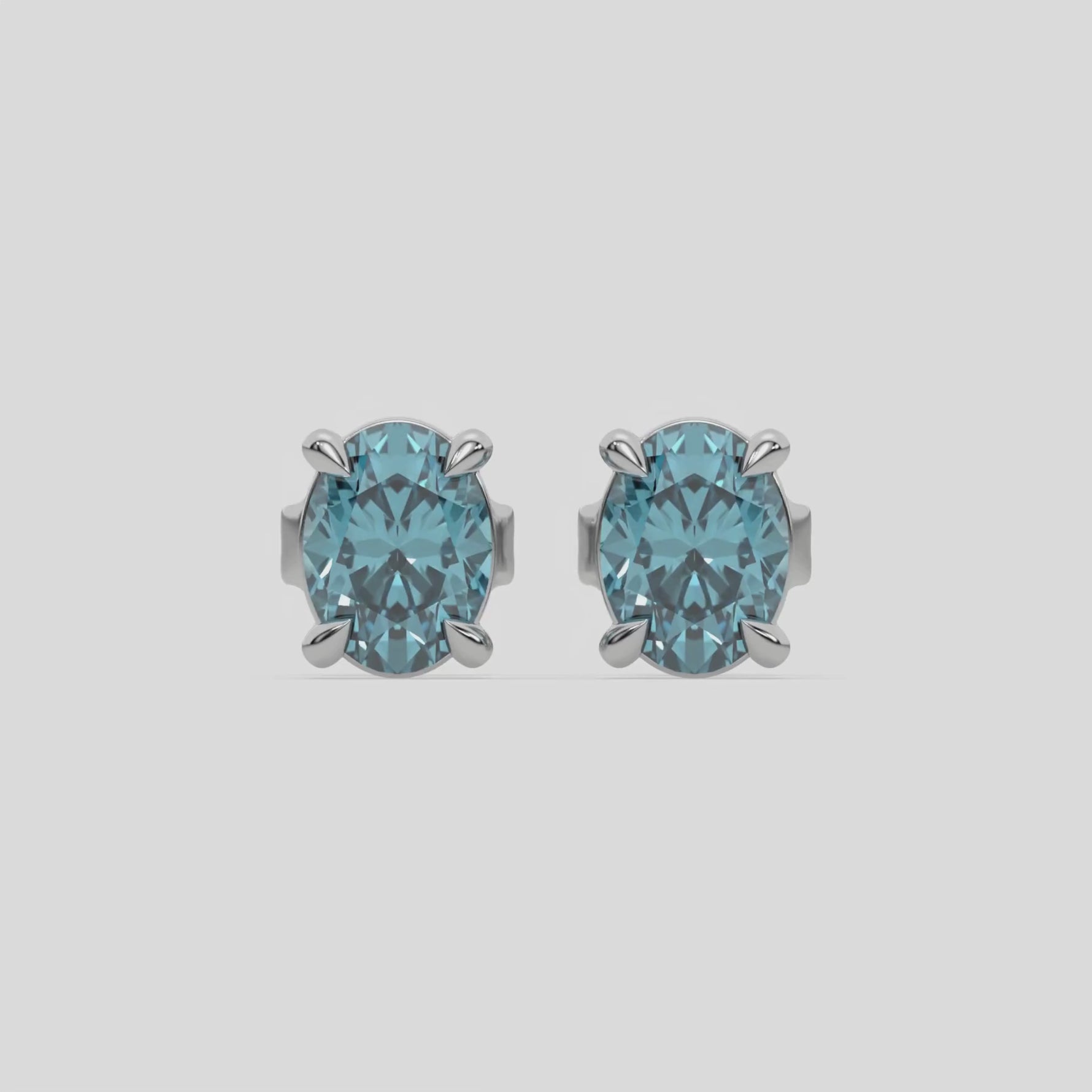 18k white gold oval diamond stud earrings made with a fancy blue oval cut diamond set in a four prong setting