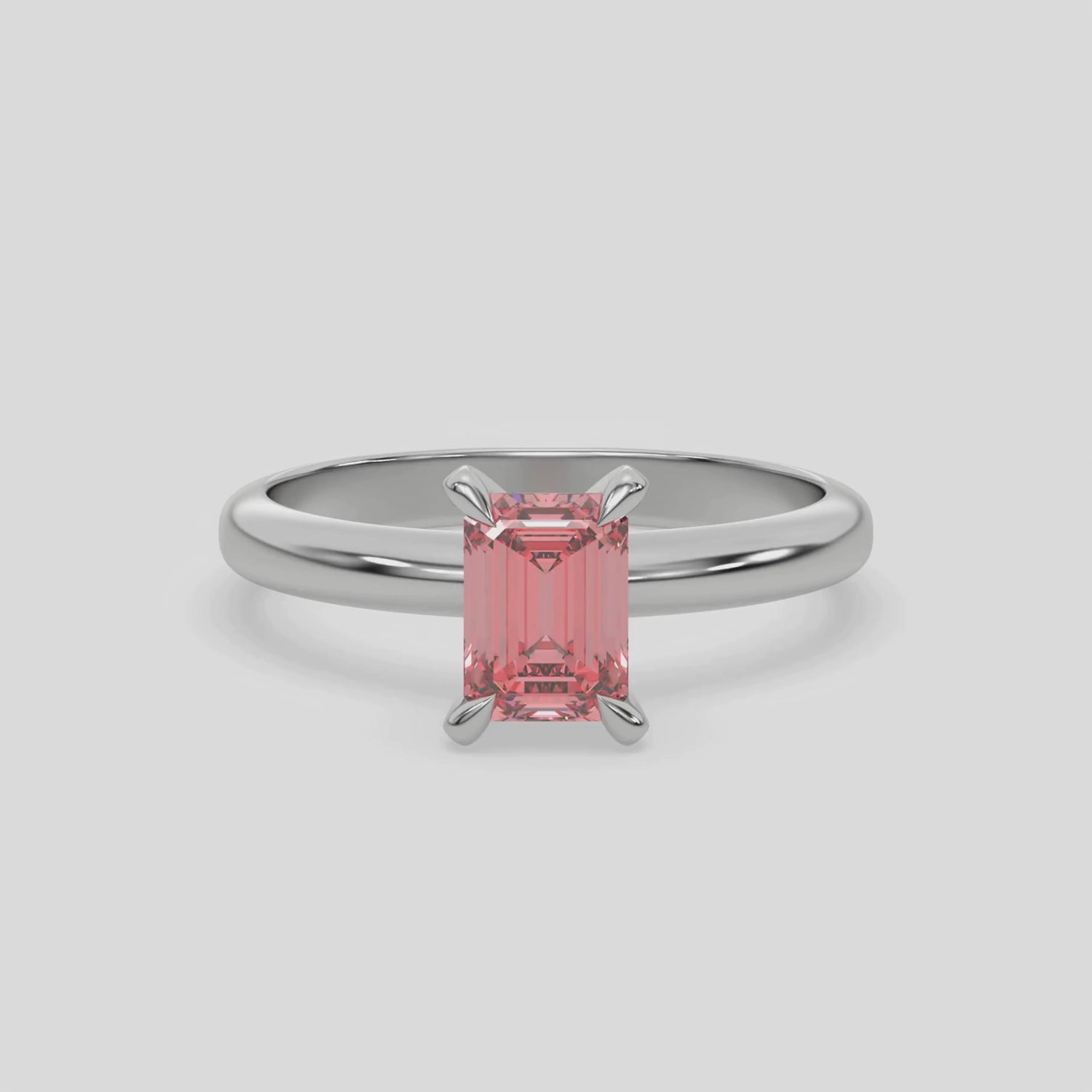 This video features a white gold ring features an fancy Pink emerald solitaire diamond elegantly secured in a four-prong setting on a solid gold band