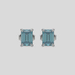 This video features a white gold Classic Emerald Diamond Earrings made with an fancy blue emerald-cut diamonds set in a four prong setting