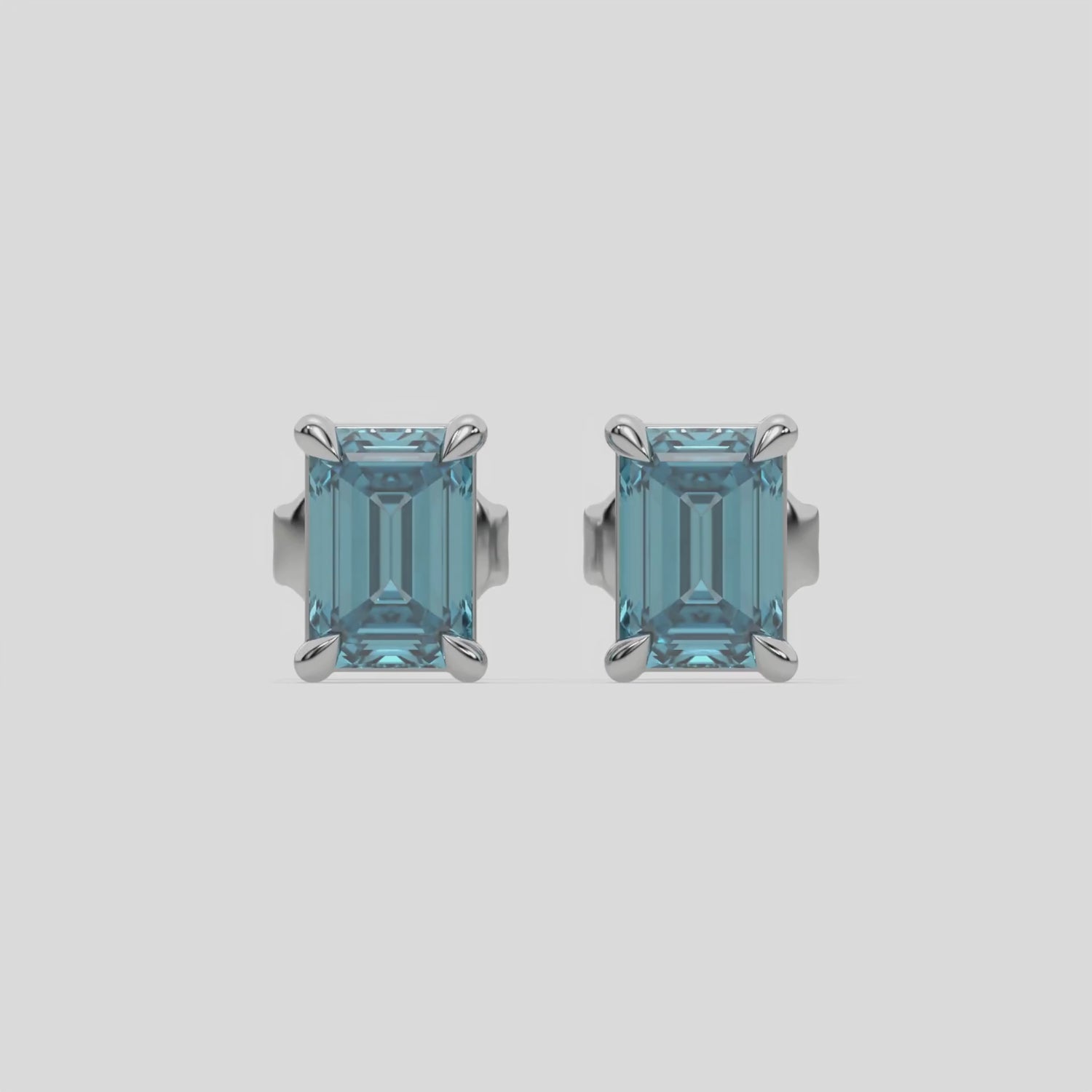 This video features a white gold Classic Emerald Diamond Earrings made with an fancy blue emerald-cut diamonds set in a four prong setting