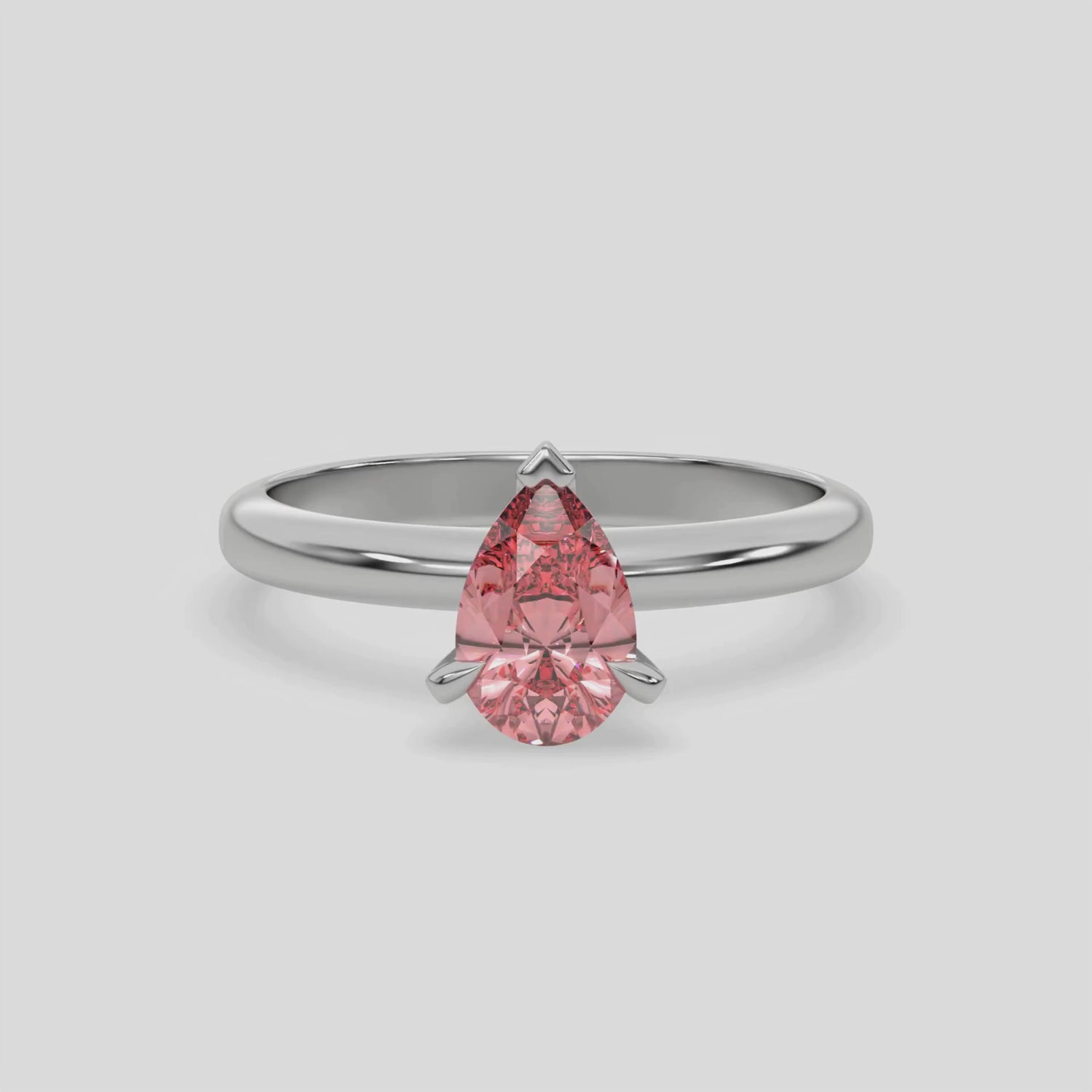 This video features a white gold ring features a fancy Pink pear solitaire diamond elegantly secured in a three-prong setting on a solid gold band