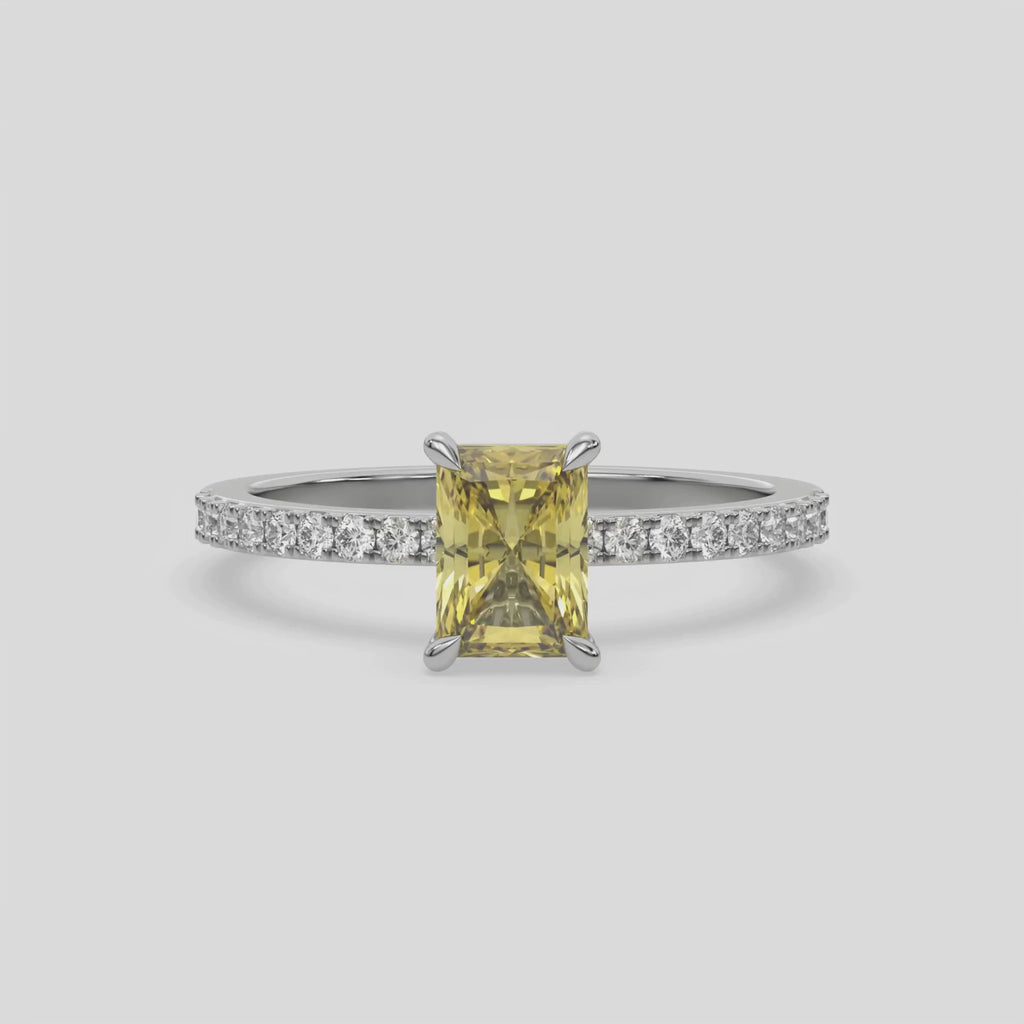 This video features a white gold ring is made with a fancy Yellow radiant solitaire diamond set in four-prong setting, and is complemented by a round pave diamonds band