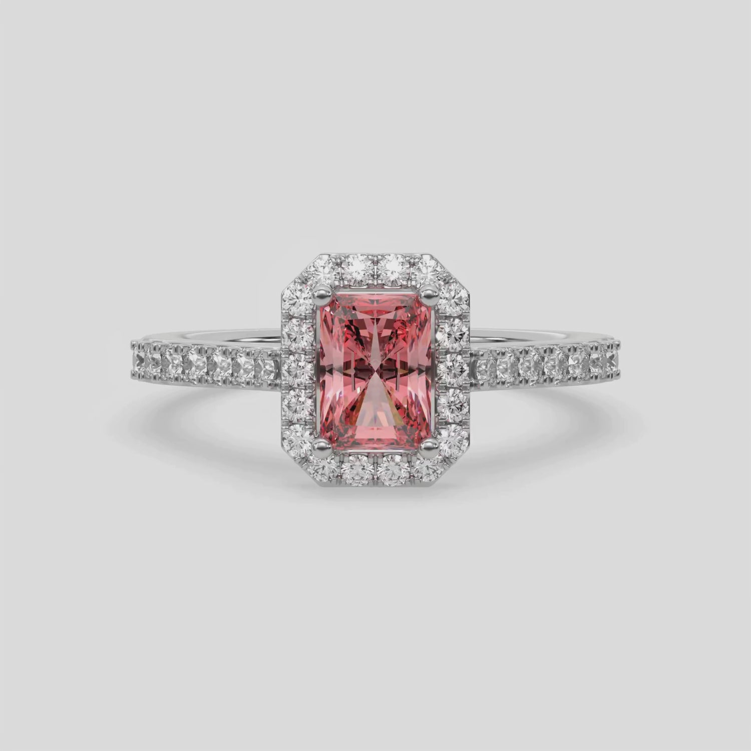 This video features a white gold Radiant Diamond Halo Engagement Ring is made with a fancy pink radiant solitaire diamond set in a four-prong setting