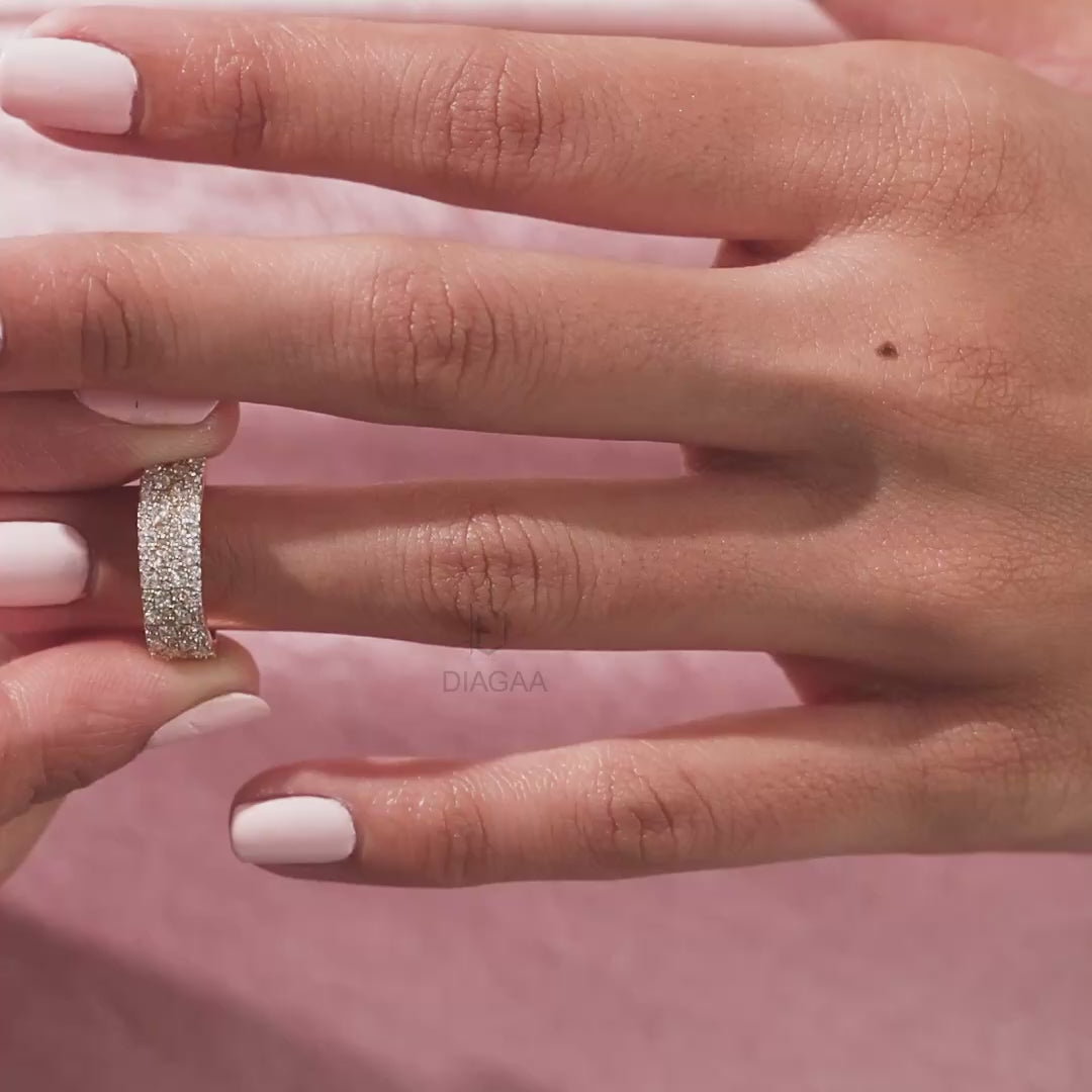 Elegant multi-row pave set princess and round diamond wedding band in 14k yellow gold , worn on a finger. A beautiful statement jewelry piece shown close up.