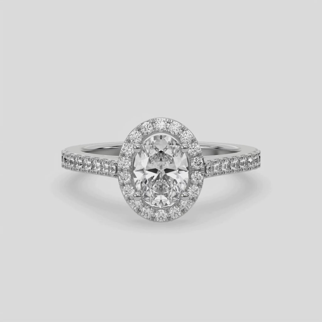 This video features a white gold Oval Diamond Halo Engagement Ring is made with an oval solitaire diamond set in a four-prong setting, surrounded by a halo of round diamonds all set on a pave band 