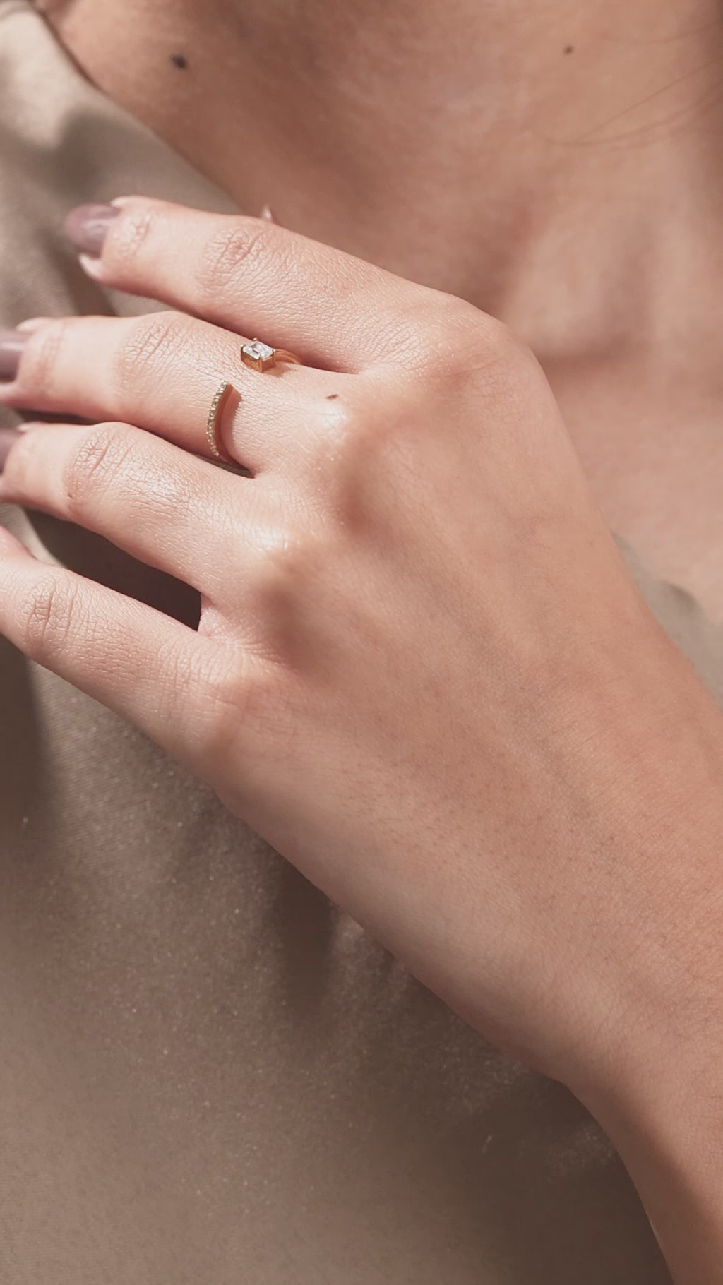 Yellow gold open cuff ring with an emerald cut diamond and micro pave round diamonds worn on a woman's hand.
