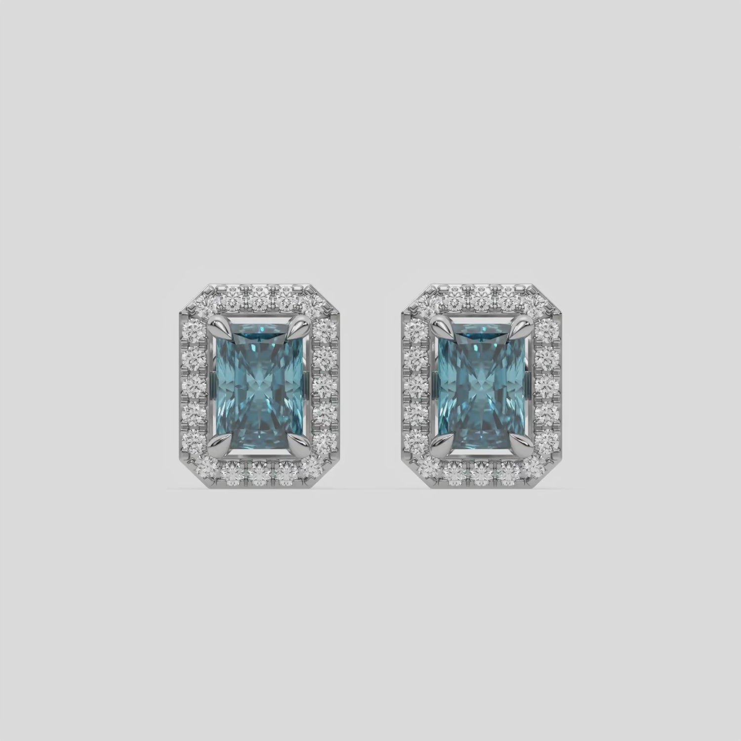 This video features a white gold Classic Radiant Diamond Halo Earrings made with a fancy Blue radiant cut solitaire diamonds set in a four prong setting