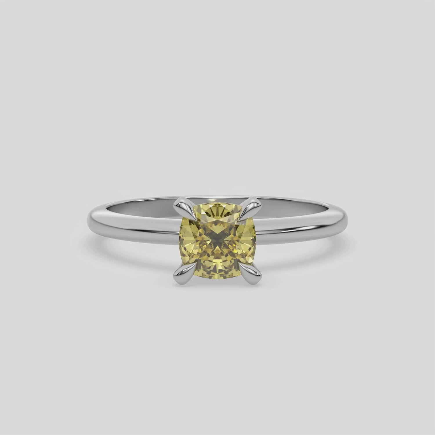 This video features a white gold ring features a fancy Yellow cushion solitaire diamond elegantly secured in a four-prong setting on a solid gold band