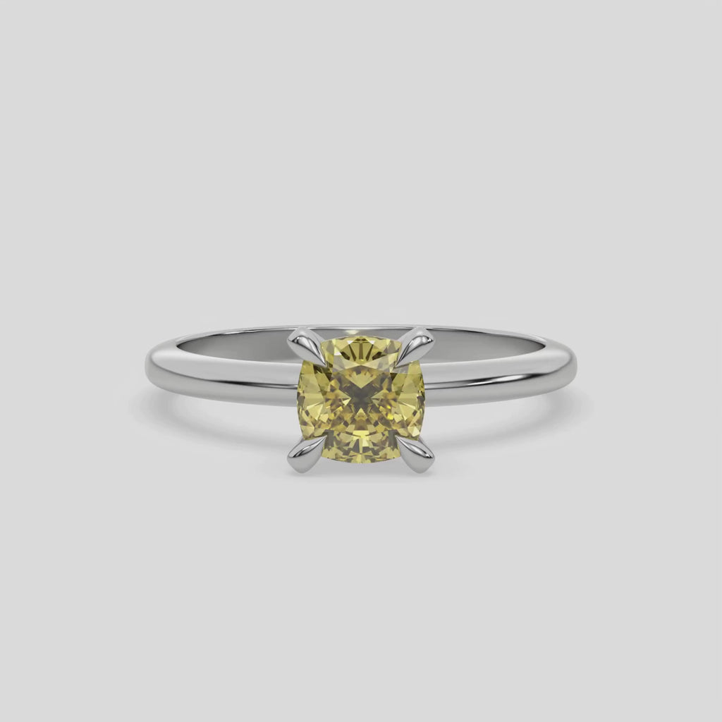 This video features a white gold ring features a fancy Yellow cushion solitaire diamond elegantly secured in a four-prong setting on a solid gold band