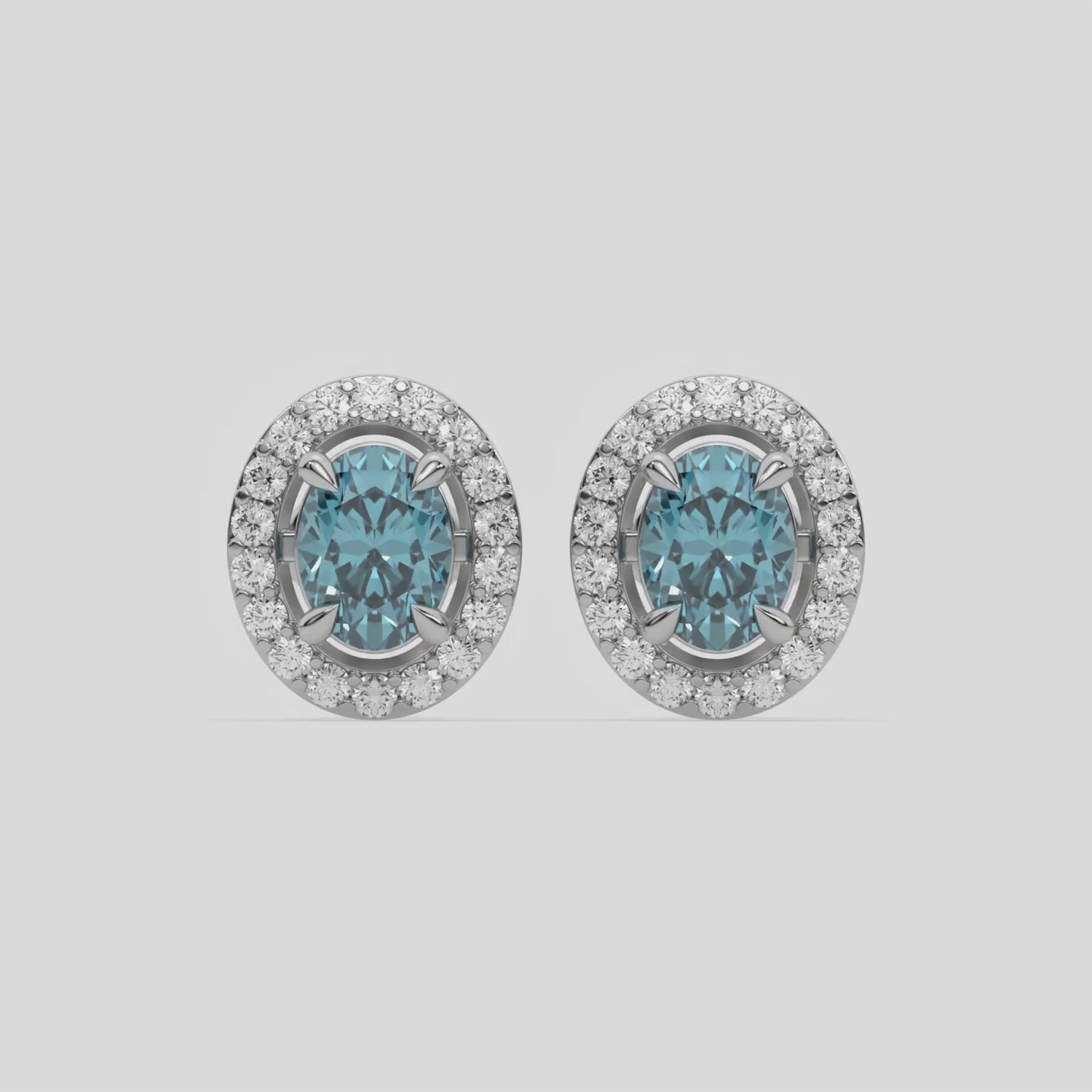 This video features a white gold Classic Oval Diamond Halo Earrings made with an fancy Blue oval cut solitaire diamonds set in a four prong setting