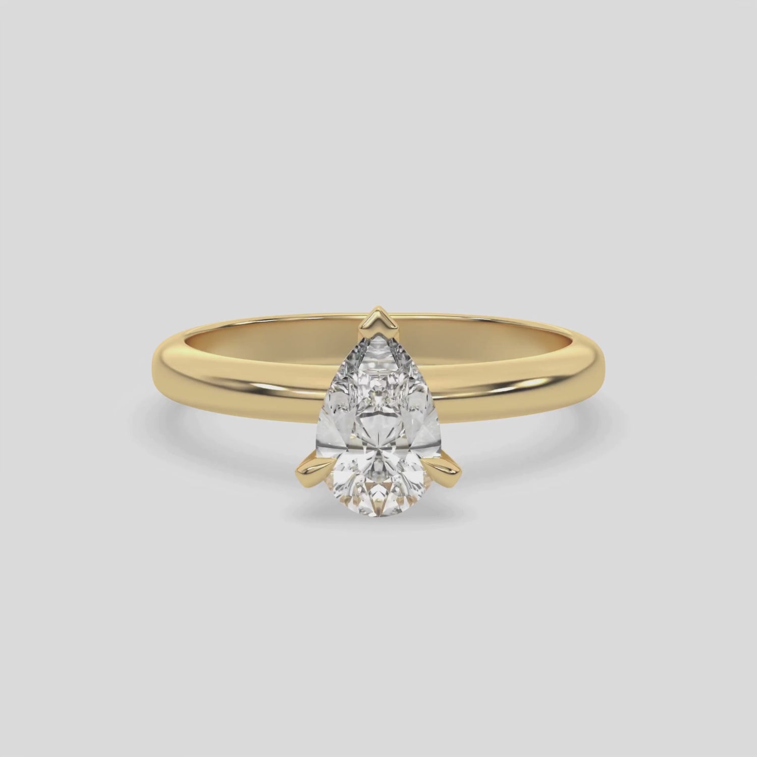 This video features a yellow gold ring features a pear solitaire diamond elegantly secured in a three-prong setting on a solid gold band 