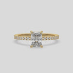 This video features a yellow gold  ring is made with a radiant solitaire diamond set in four-prong setting, and is complemented by a round pave diamonds band