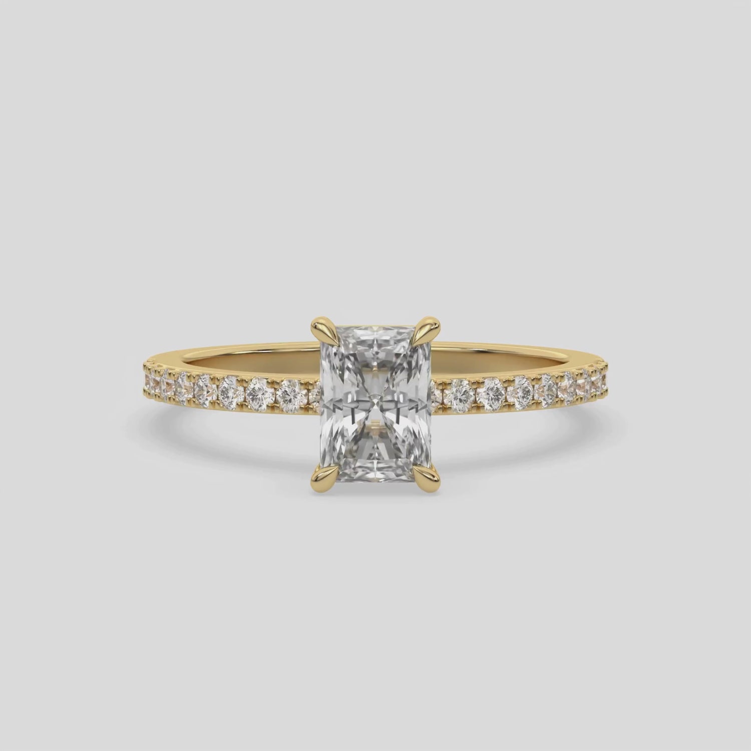 This video features a yellow gold  ring is made with a radiant solitaire diamond set in four-prong setting, and is complemented by a round pave diamonds band