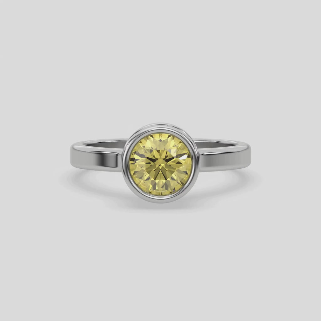 This yellow gold ring displayed on front view is made with brilliant round solitaire diamond set in bezel setting