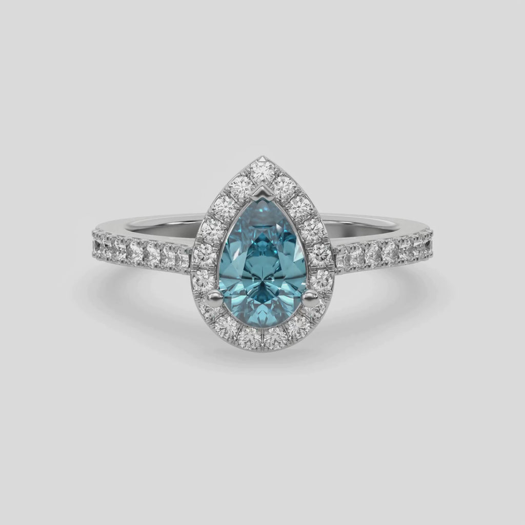 This video features a white gold Pear Diamond Halo Engagement Ring is made with a fancy blue pear solitaire diamond set in a four-prong setting