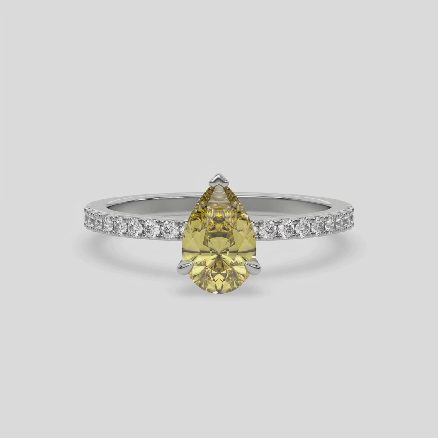 This video features a white gold ring is made with a fancy Yellow pear solitaire diamond set in three-prong setting, and is complemented by a round pave diamonds band