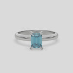 This video features a white gold ring features an fancy Blue emerald solitaire diamond elegantly secured in a four-prong setting on a solid gold band 