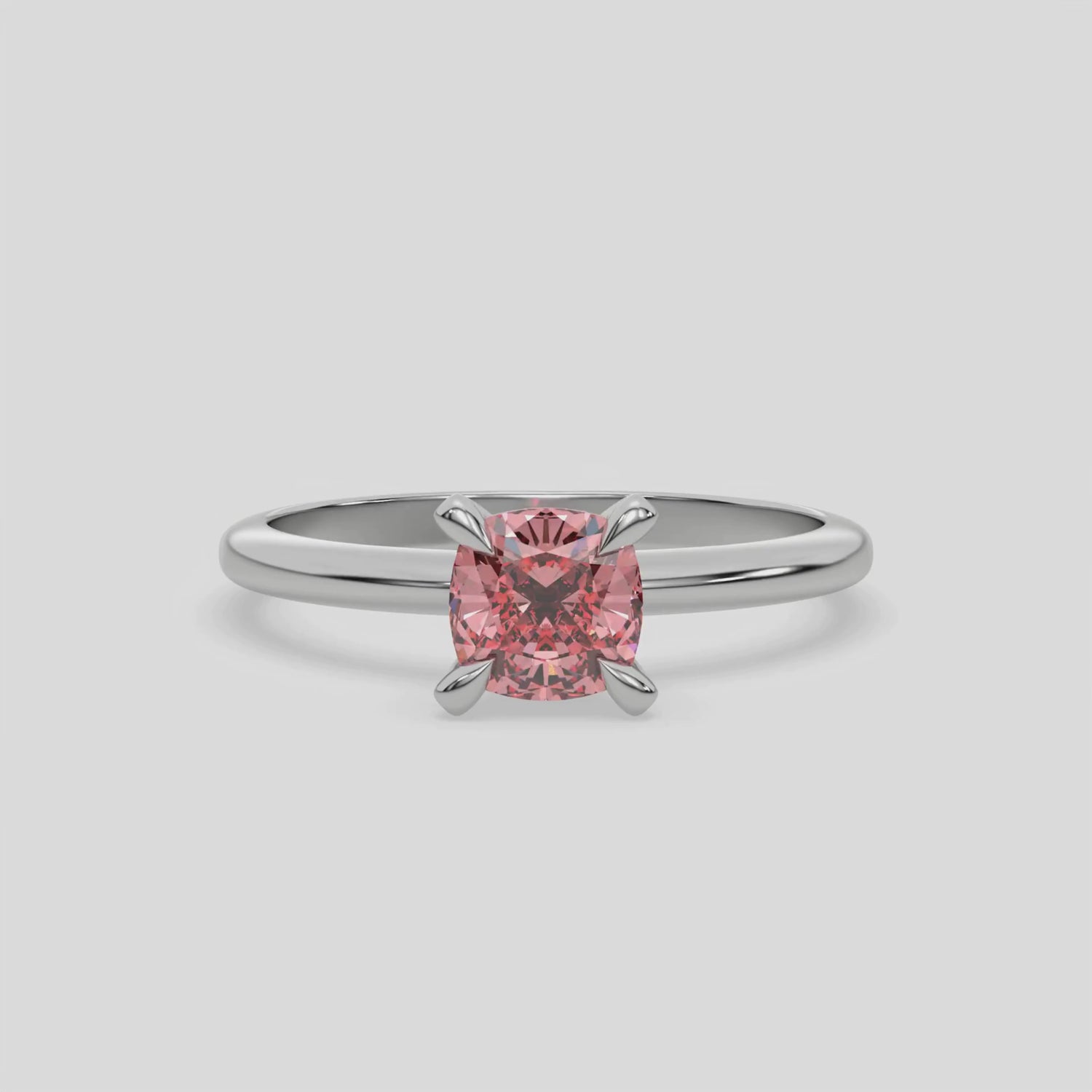 This video features a white gold ring features a fancy Pink cushion solitaire diamond elegantly secured in a four-prong setting on a solid gold band