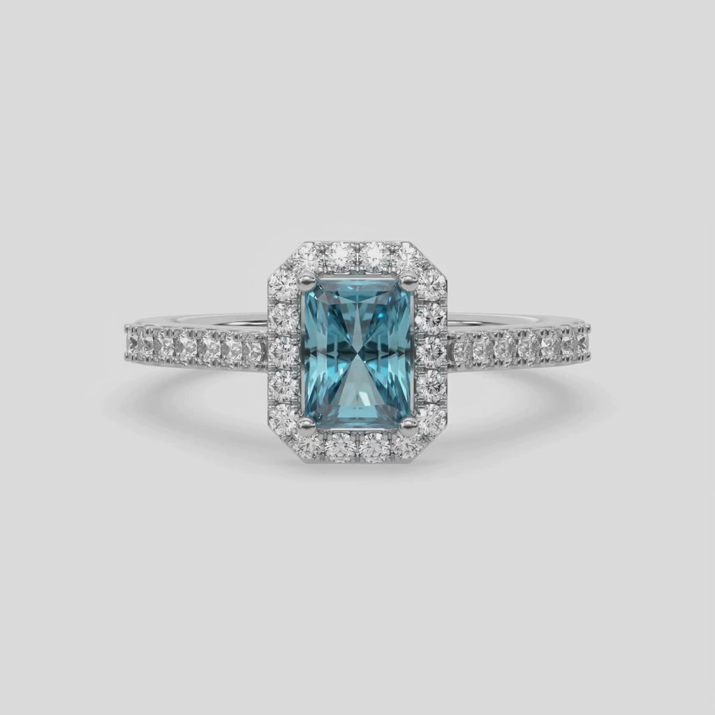 This video features a white gold Radiant Diamond Halo Engagement Ring is made with a fancy Blue radiant solitaire diamond set in a four-prong setting