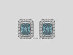 14k white gold Radiant Diamond Halo Earrings made with a fancy blue radiant cut solitaire diamond set in a four prong setting.