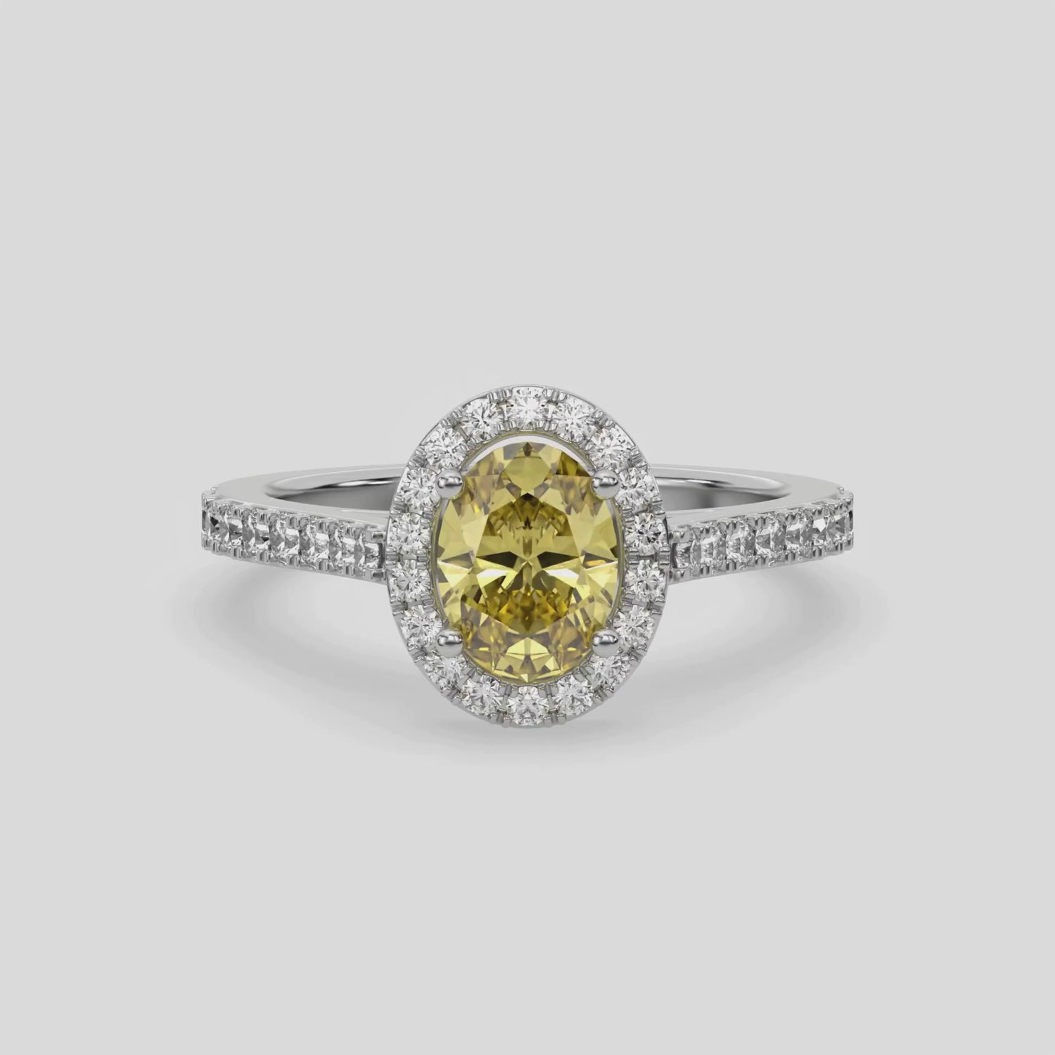 This video features a white gold Oval Diamond Halo Engagement Ring is made with a fancy yellow oval solitaire diamond set in a four-prong setting, surrounded by a halo of round diamonds all set on a pave band